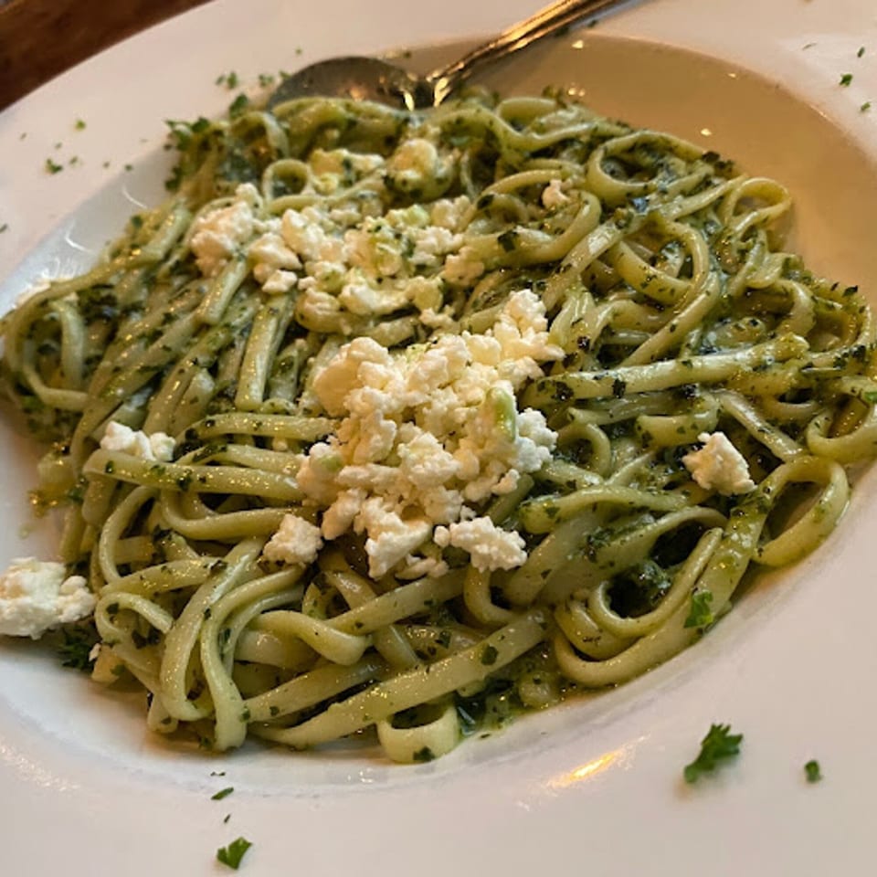 Gabriella's linguine pasta with pesto sauce and crumbled feta cheese on a white plate.